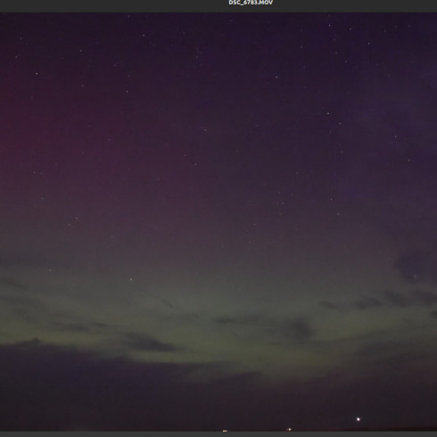 a long exposure view of green aurorae and clouds